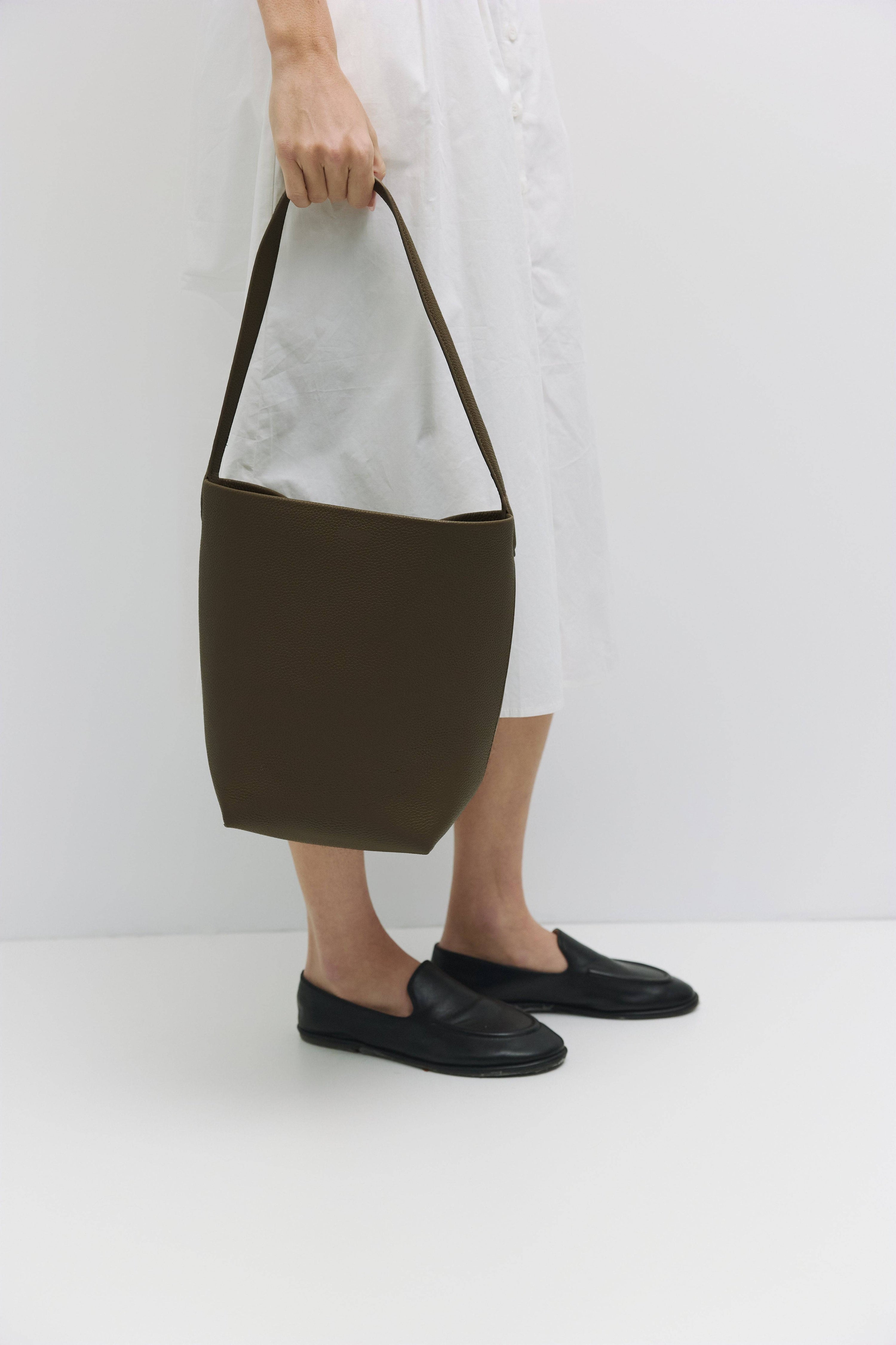 8857782157533, The Elise Tote Bag, Bags, Mod Ref | Common Market, accessories,bag,bags,cf-color-khaki,cf-color-white,cf-vendor-mod-ref-common-market,dark brown,modrefcommonmarket,Oversized,purse, Information The Elise Tote Bag features a top tie closure and an integrated leather shoulder strap for a simple yet functional design. The removable inner lining offers extra versatility, allowing you to easily clean or switch up the interior as needed. Details 100% Cowhide Top Tie Closure Leather Shoulder Strap Re