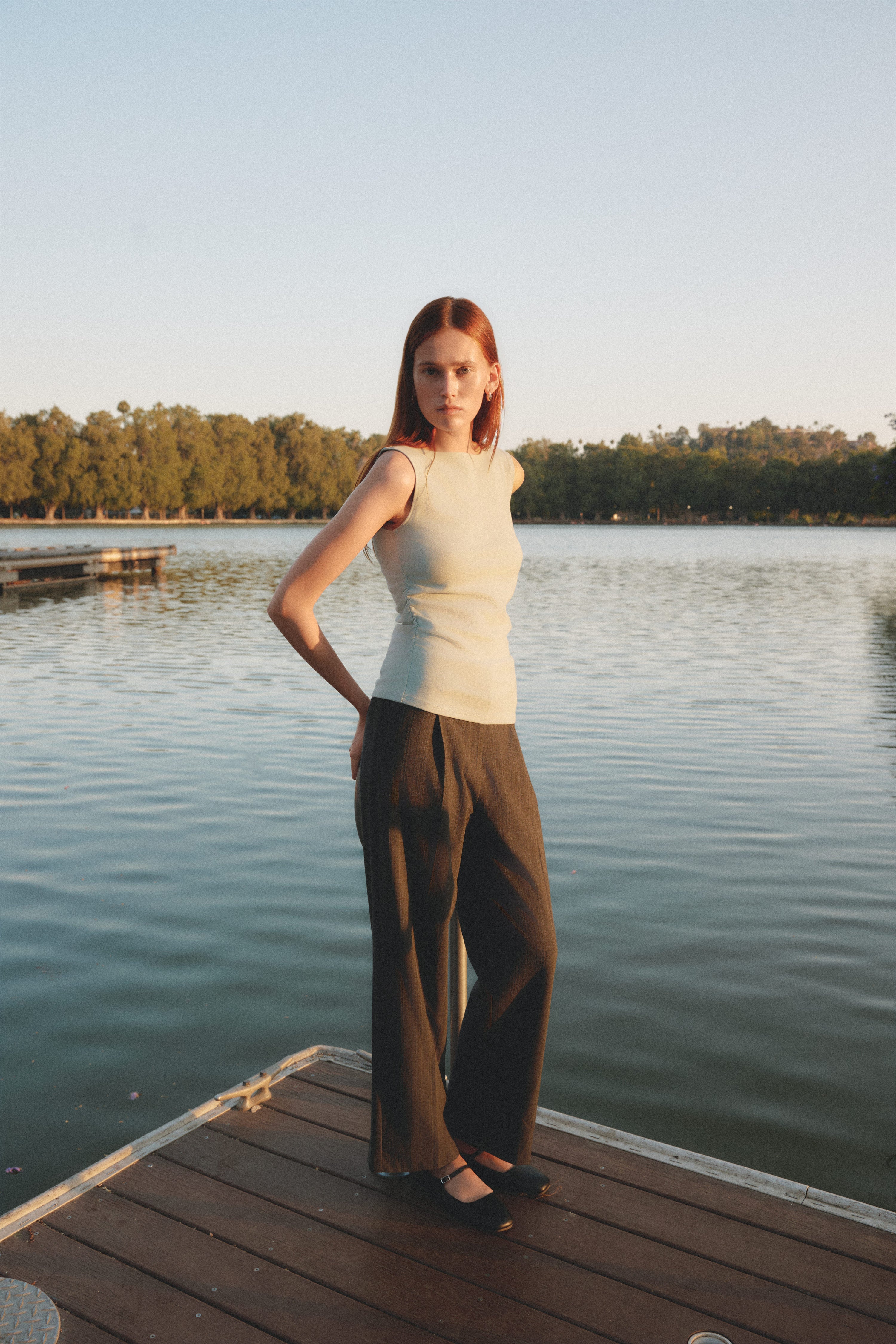 Woman standing on a dock by a lake with trees in the background