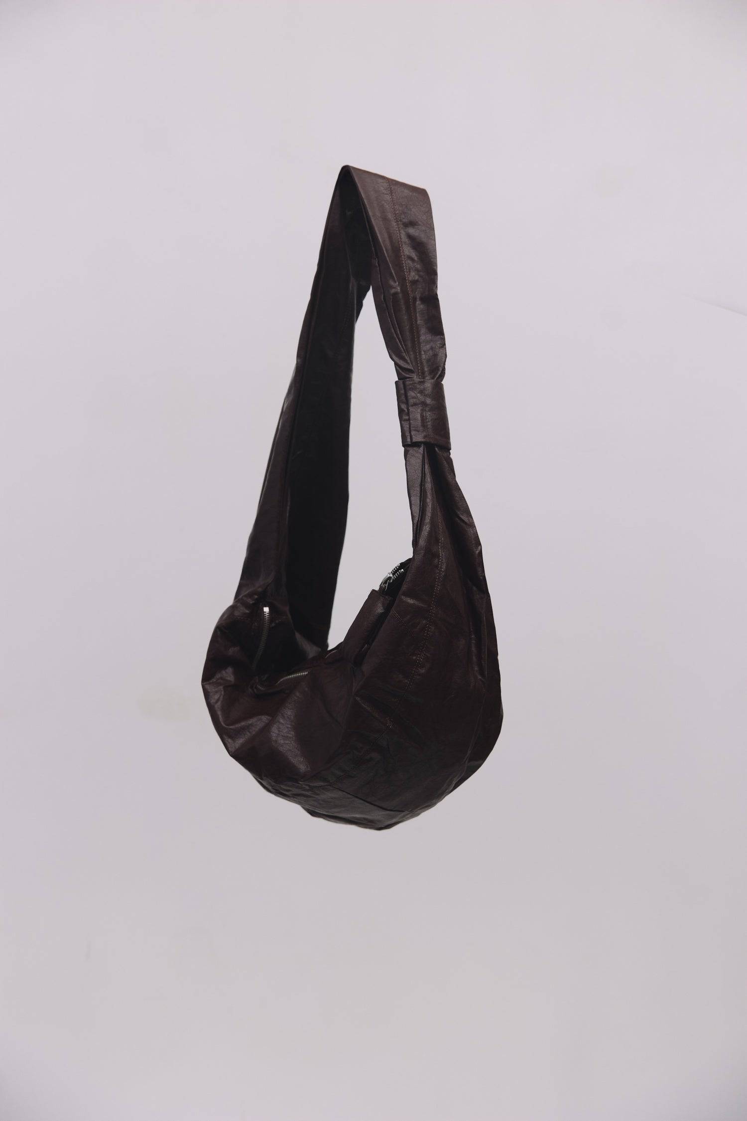 8989192388829, The Charli Bag, Bags, Mod Ref | Common Market, accessories,bag,bags,Black,cf-vendor-mod-ref-common-market,modrefcommonmarket,purse, Information The Charli Bag is a medium-sized crescent sling crafted from glossy distressed leather. It features a sleek curved silhouette, a durable zipper closure, reinforced stitching, and a roomy single compartment. Designed to be worn crossbody or over the shoulder, it’s finished with a matching looped zipper pull and knit detailing along the sides. Details G