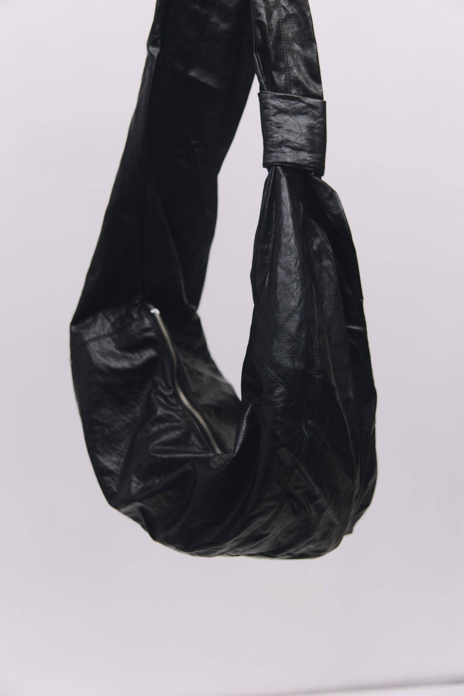 8989192388829, The Charli Bag, Bags, Mod Ref | Common Market, accessories,bag,bags,Black,cf-vendor-mod-ref-common-market,modrefcommonmarket,purse, Information The Charli Bag is a medium-sized crescent sling crafted from glossy distressed leather. It features a sleek curved silhouette, a durable zipper closure, reinforced stitching, and a roomy single compartment. Designed to be worn crossbody or over the shoulder, it’s finished with a matching looped zipper pull and knit detailing along the sides. Details G