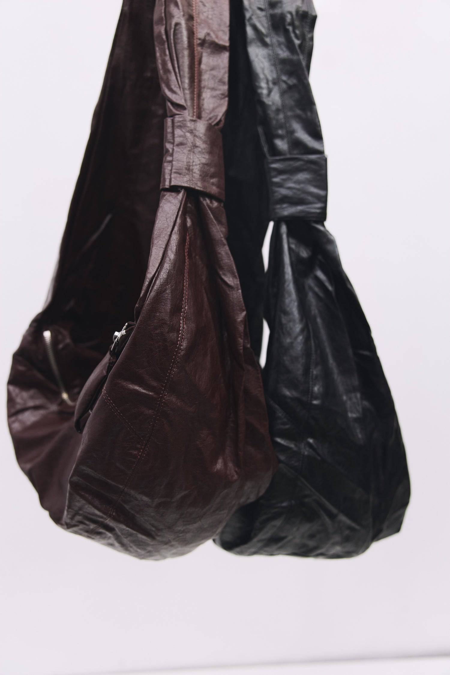 8989192388829, The Charli Bag, Bags, Mod Ref | Common Market, accessories,bag,bags,Black,cf-vendor-mod-ref-common-market,modrefcommonmarket,purse, Information The Charli Bag is a medium-sized crescent sling crafted from glossy distressed leather. It features a sleek curved silhouette, a durable zipper closure, reinforced stitching, and a roomy single compartment. Designed to be worn crossbody or over the shoulder, it’s finished with a matching looped zipper pull and knit detailing along the sides. Details G