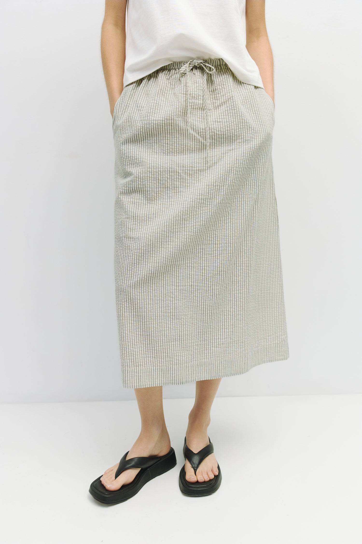 8929228947677, The Genevieve Skirt, Bottoms, Mod Ref, adjustable,Adjustable Cords,Casual,cf-size-l,cf-size-m,cf-size-s,cf-size-xl,cf-size-xs,Comfortable,cotton,Everyday,final-sale,finalsale,Maxi,midi length,Midi Skirt,new,Pinstripes,Pocket,Pockets,Relaxed,Relaxed Fit,sale,seersucker,side pockets,Skirt,Striped,texture,Women's, Information The Genevieve Skirt is a midi-length skirt designed with a lightweight seersucker fabric, featuring an elasticized waistband and front tie for a comfortable fit. With a str