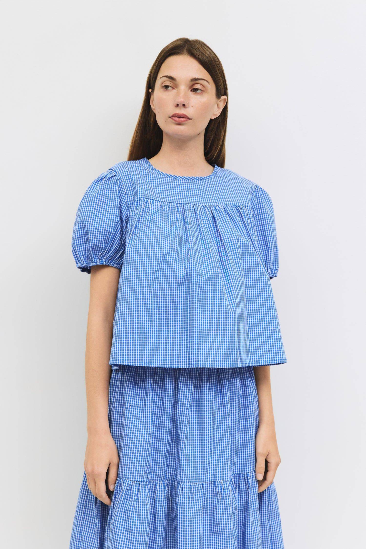 8994150711517, The Carroll Top, Tops, All Row, back tie,Black,Blue,brown,cf-color-blue,cf-color-brown,cf-color-lightblue,cf-size-l,cf-vendor-all-row,collared,Comfort,Comfortable,Cropped,cropped hemline,Feminine,gingham,Light Blue,new,plaid,Puff Sleeve,semi-cropped,Spring,versatile,Womens, Information The Carroll Top is a lightweight gingham blouse with short puff sleeves and an elastic hem for a relaxed, feminine fit. Featuring a center back tie closure and sheer front and back yokes, it’s an easy-to-wear p