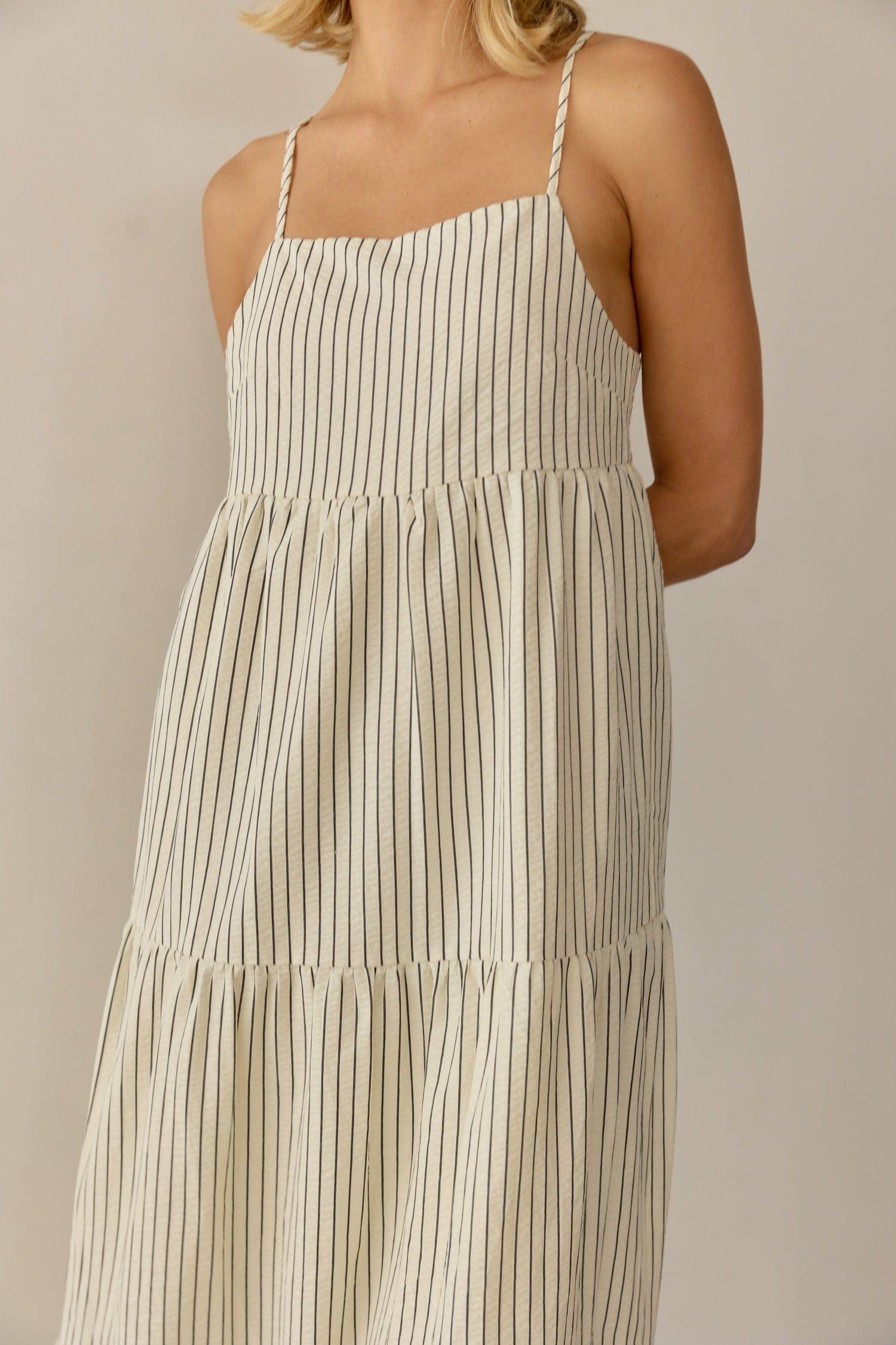 8668654895325, The Aspen Dress, Dress, All Row, adjustable straps,Casual,cf-color-cream,cf-size-l,cf-vendor-all-row,Comfort,Comfortable,Cream,Dress,Feminine,full skirt,Midi,Midi Dress,midi length,new,open back,Pinstripes,Pockets,Semi-Formal,Sleeveless,Sleeveless Dress,Spring,Stripe,Striped,Stripes,Summer,Tiered Dress,versatile,Warm,warm weather,Womens, Information The Aspen Dress is a striped seersucker tiered midi dress that features a square neckline, adjustable shoulder straps, and a back tie detail for 